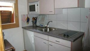 A compact kitchen with white cabinets, a stainless steel sink, and a microwave. - Farbhaus Bleiche by Interhome (Rohrbach)