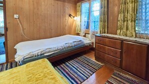 Ett rum med träpanel på väggarna, en säng, en byrå och ett fönster med gardiner.