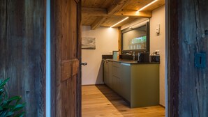 A wooden-framed doorway leading to a kitchen with a wooden ceiling, a sink, and cabinets.