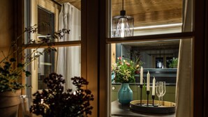 A window with a view of a balcony, a vase with flowers, and two wine glasses.