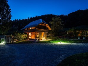 A wooden house with a sloped roof, a front porch, and a gravel driveway.