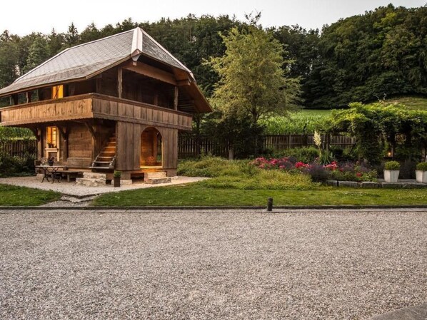 A wooden cabin with a sloped roof, a porch, and a staircase leading to the entrance.