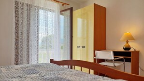 Una camera da letto con un letto, una scrivania in legno, una sedia, un armadio e una lampada.