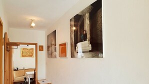Un corridoio con una panca di legno, un tavolino e un armadietto in legno. Tre quadri appesi alla parete.