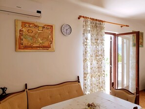 A room with a bed, a table with a tablecloth, a clock, a map, and a window with curtains. - Apartment Bijelic - 480 Meter vom Meer by Interhome (Krk/Šilo)