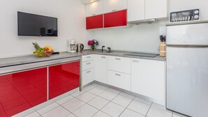 Une cuisine moderne avec des meubles blancs et rouges, un four encastré et une machine à café.