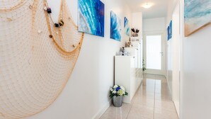 Un couloir décoré d’un filet, avec un réfrigérateur et plusieurs tableaux accrochés au mur.