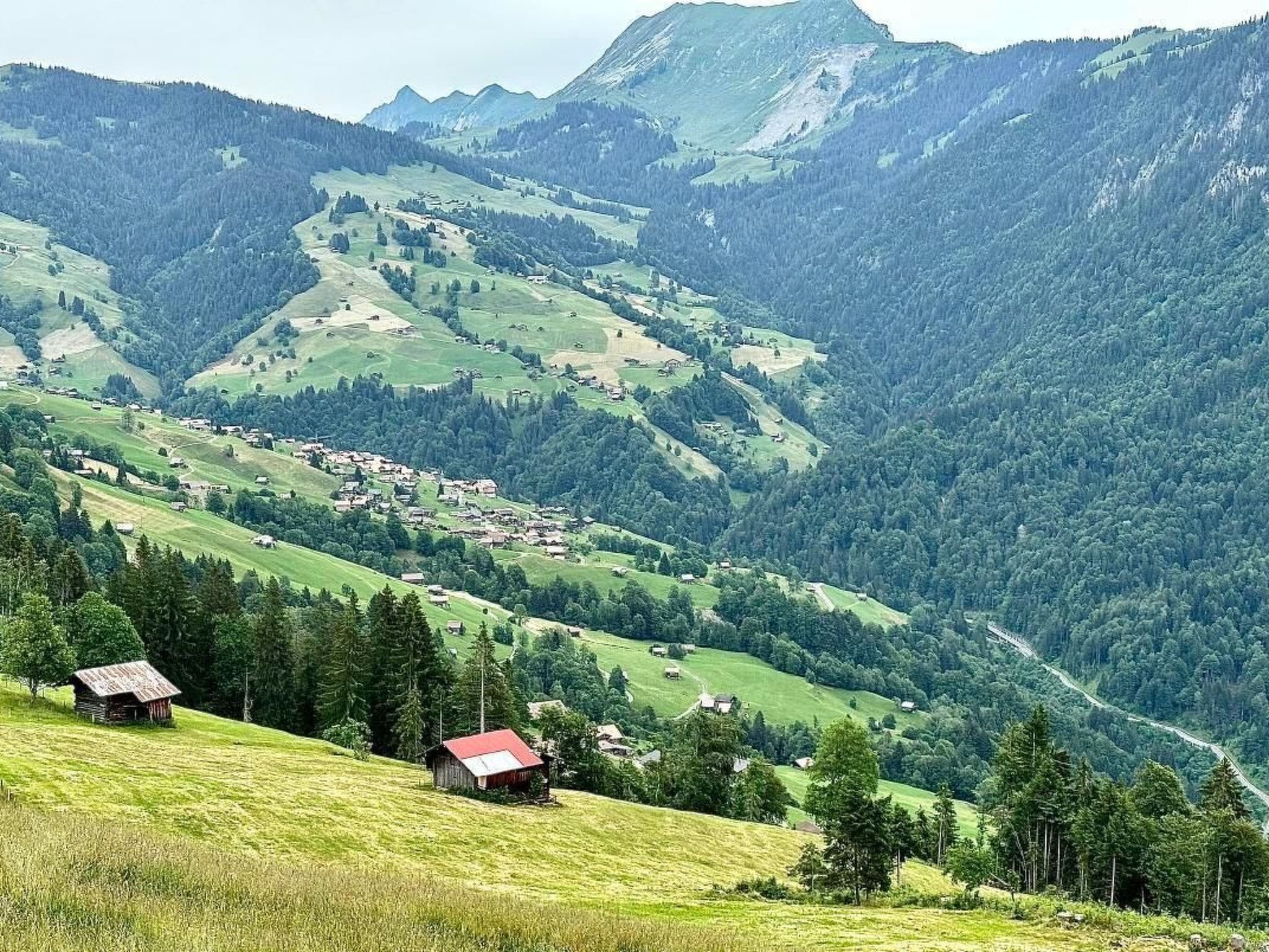 A rural landscape with rolling hills, a small village, and a mountain range in the background.