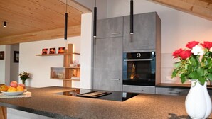 Una cocina moderna con encimera de granito, horno empotrado e iluminación colgante.