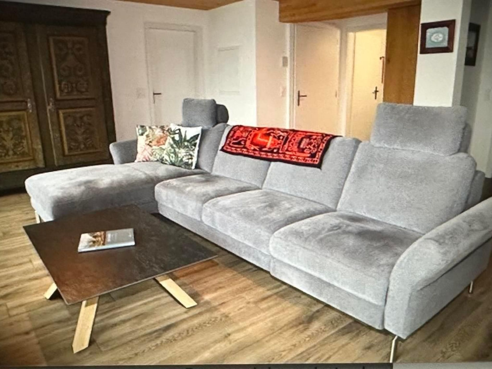 Una sala de estar con un sofá gris, una mesa de centro de madera y una manta con estampado.
