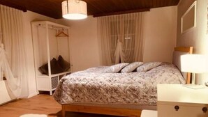 Une chambre à coucher comprenant un lit, une table de chevet, une armoire et un fauteuil suspendu.