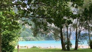 Un parc doté de bancs en pierre, d’une pelouse et offrant une vue sur un lac avec un pont en arrière-plan.