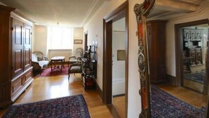 Un hall d’entrée spacieux, doté d’un parquet en bois, d’un grand miroir décoratif et d’un fauteuil traditionnel.