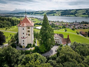 A castle with a red roof, surrounded by lush green fields and a lake. - Schloss Heidegg by Interhome (Gelfingen)