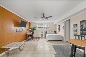 Un dormitorio moderno con cama, escritorio, silla y ventilador de techo.