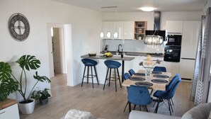 A modern kitchen with a central island, bar stools, and pendant lighting. - mit Blick auf das Wasser by Interhome (Orebić)