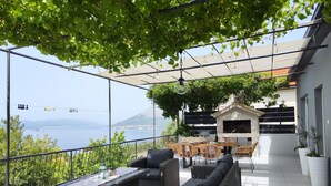 A covered outdoor seating area with wicker furniture, a barbecue grill, and a view of the sea. - mit Blick auf das Wasser by Interhome (Orebić)