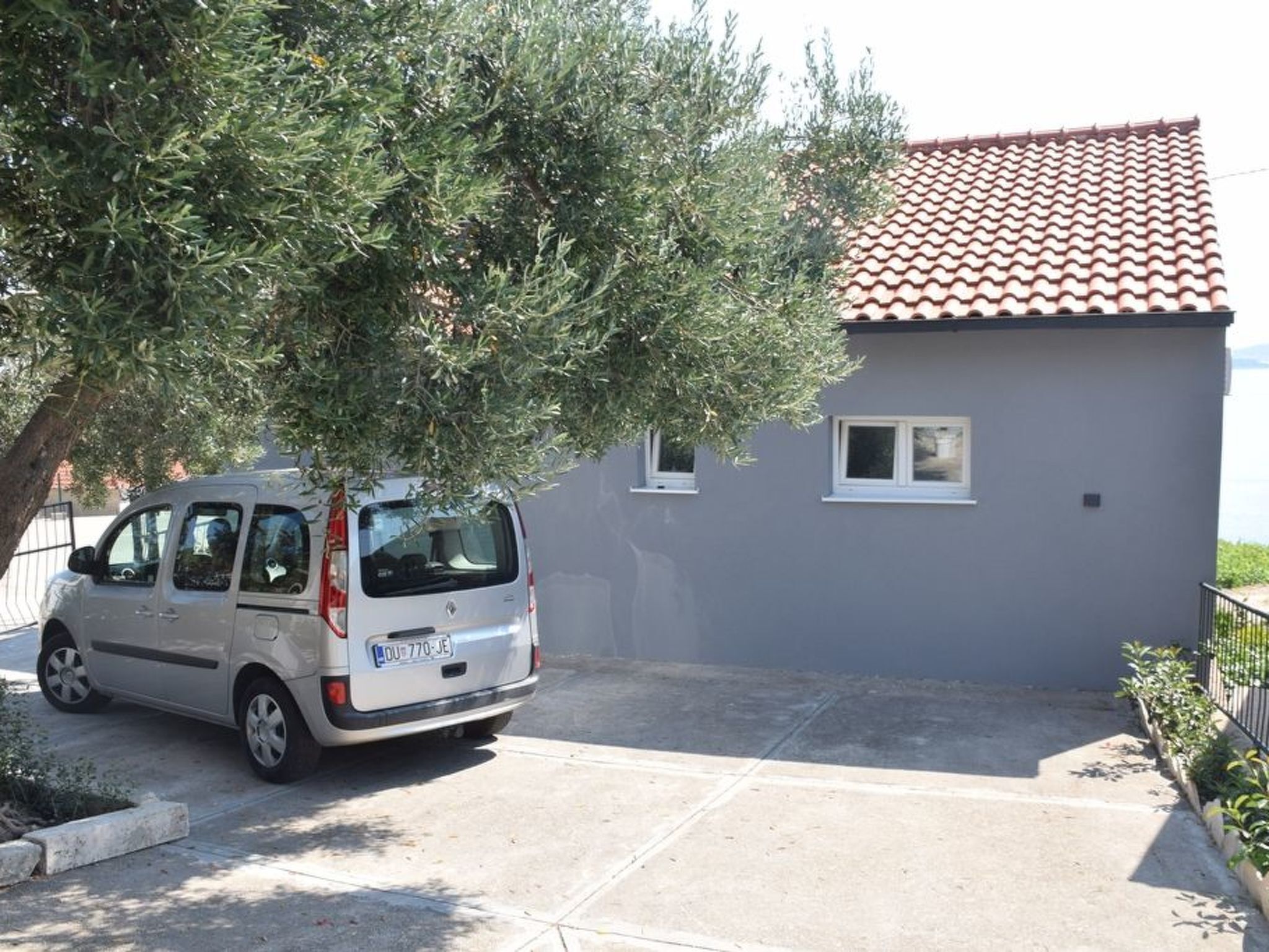A small, single-story building with a tiled roof and a parked car in front.