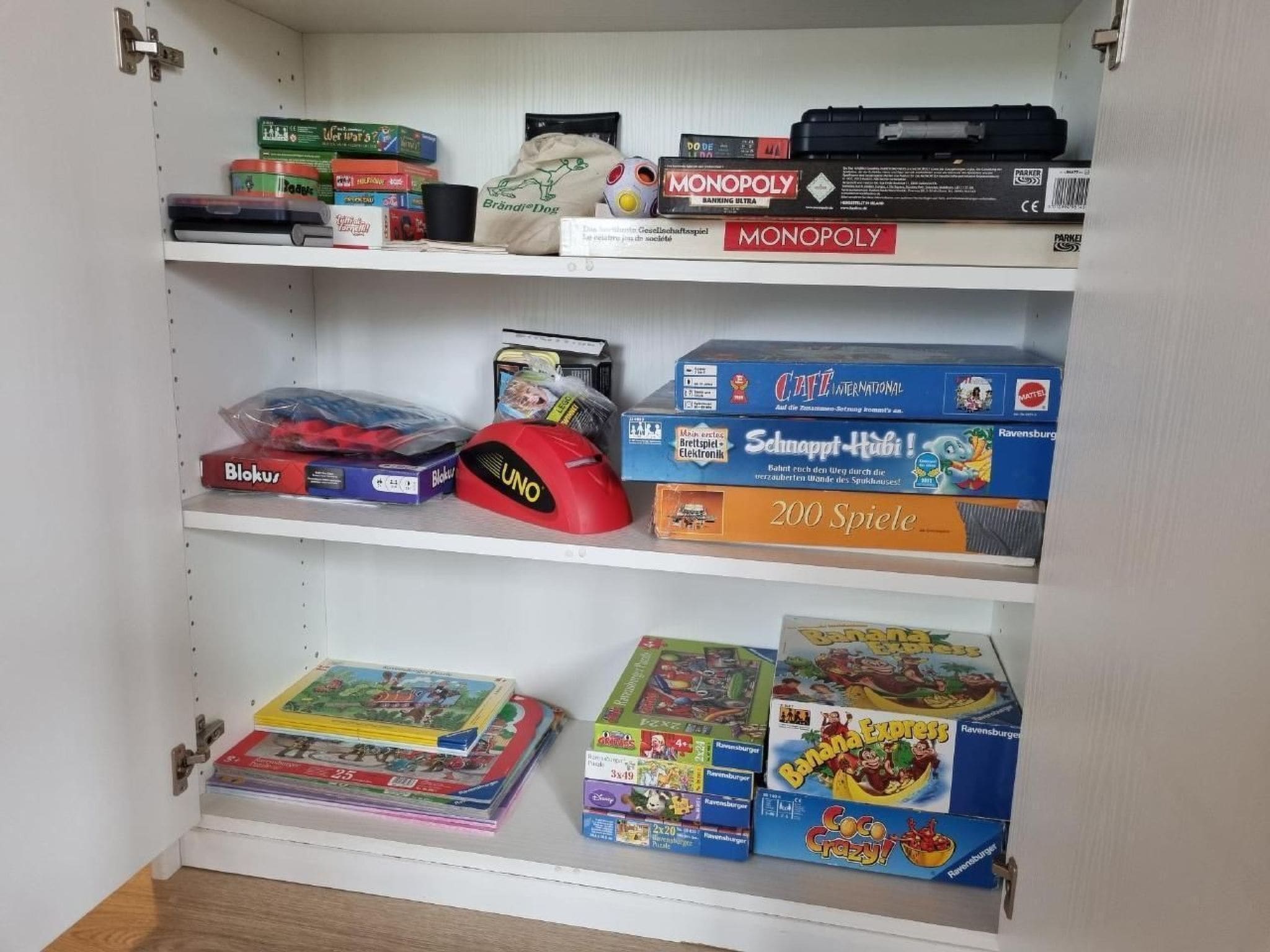 Ein Regal mit verschiedenen Gesellschaftsspielen, darunter Monopoly, UNO und Catan.