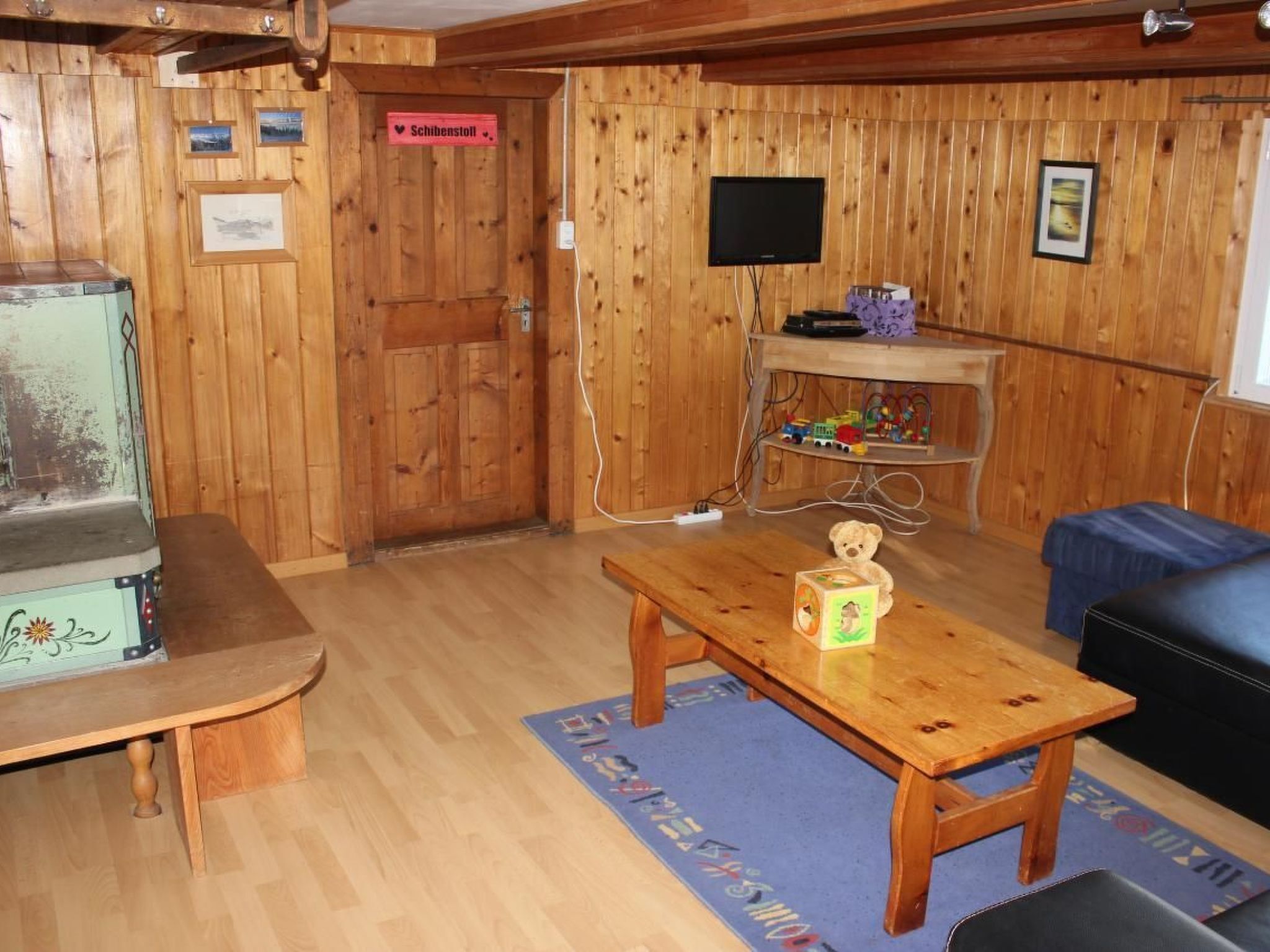 Un interno in legno con un tavolo di legno, una televisione e un cartello con scritto "Schibenstoll".