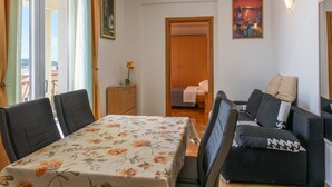 A room with a dining table, chairs, a sofa, a small cabinet, and a painting on the wall. - mit Whirlpool by Interhome (Trogir)
