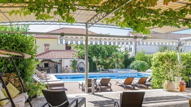 A covered outdoor pool area with lounge chairs and a pergola overhead. - mit Whirlpool by Interhome (Trogir)