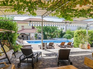 A covered outdoor pool area with lounge chairs and a pergola overhead. - mit Whirlpool by Interhome (Trogir)