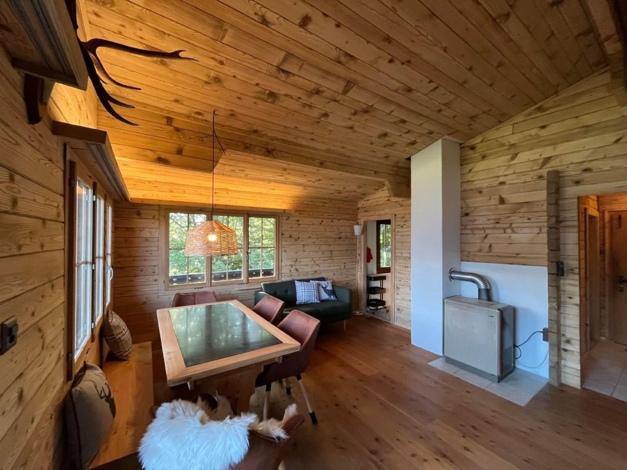 Ein Holzblockhaus-Innenraum mit Essbereich, Sofa und einer kleinen Küchenzeile.