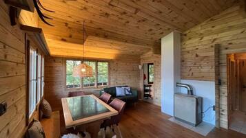 Ein Holzblockhaus-Innenraum mit Essbereich, Sofa und einer kleinen Küchenzeile.