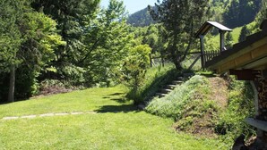 A well-maintained garden with a wooden bench, a stone pathway, and a small gazebo.