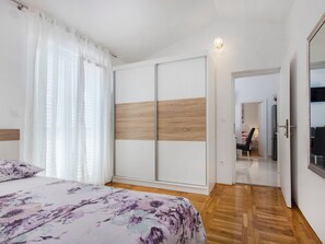 Ein Schlafzimmer mit Bett, Kleiderschrank und einer Tür zu einem anderen Raum.