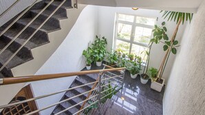 Um interior moderno com escada, plantas em vasos e uma janela grande.