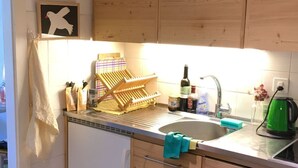 Une cuisine avec des meubles de rangement en bois, un évier et un tapis à rayures.