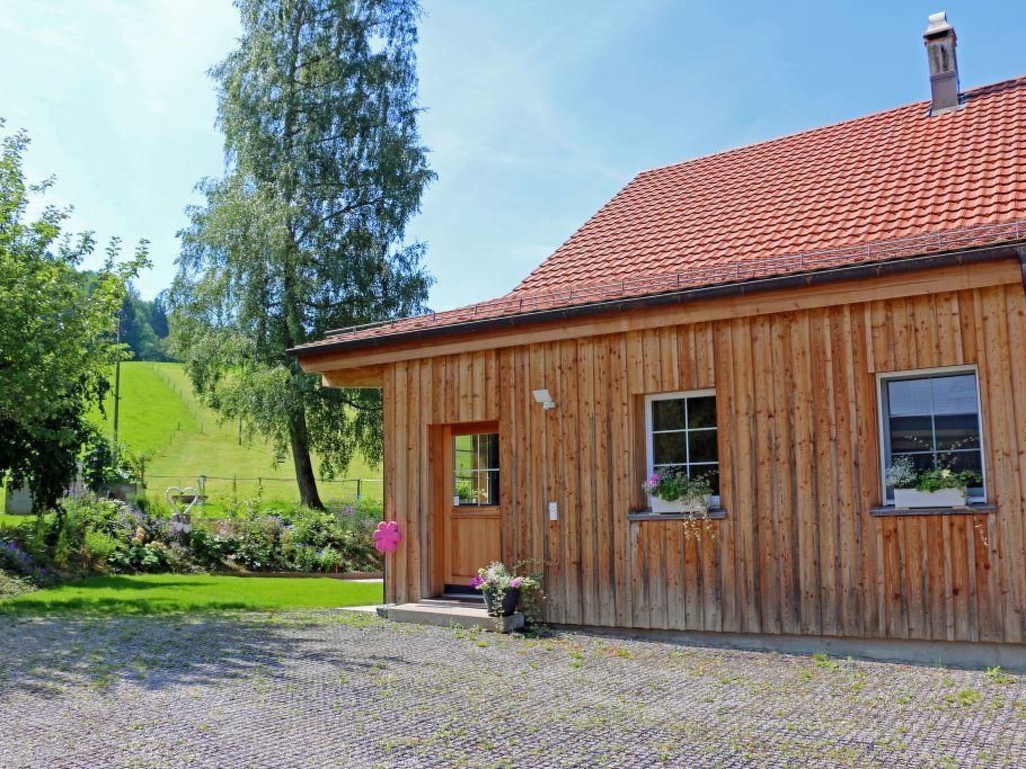 A wooden cabin with a red-tiled roof, a wooden door, and a window.
