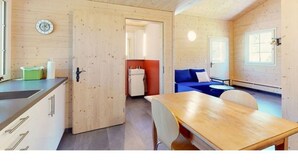 Ein gemütlicher Raum mit Holzbalkendecke, Esstisch, Sofa und einer Küchenzeile.