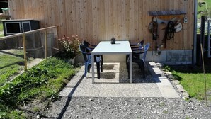 Een buitenplaats met een tafel en stoelen, een kleine tuin en een houten muur.