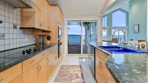 Una cocina con armarios de madera, encimera negra y vistas al exterior.