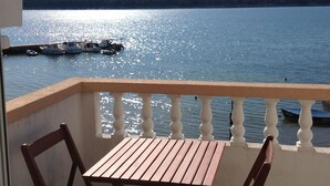 A balcony with a wooden table and chairs overlooking a calm lake with boats. - Wohnung 1 mit Meerblick by Interhome (Rab/Rab)