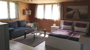 Une pièce confortable, aménagée comme un chalet, avec un canapé, un lit, une petite table et un tableau accroché au mur.