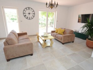 A living room with two sofas, a coffee table, a wall clock, and a TV. - Alleinstehendes Ferienhaus mit Swimmingpool by Interhome (Tijarica)