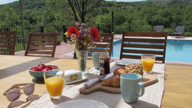Una colazione con tavolo, sedie, piscina e una vista panoramica.