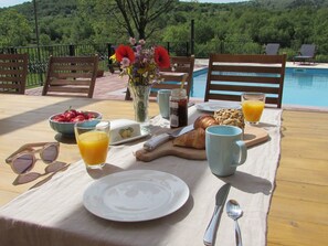 A breakfast setup with a table, chairs, a pool, and a scenic view. - Alleinstehendes Ferienhaus mit Swimmingpool by Interhome (Tijarica)