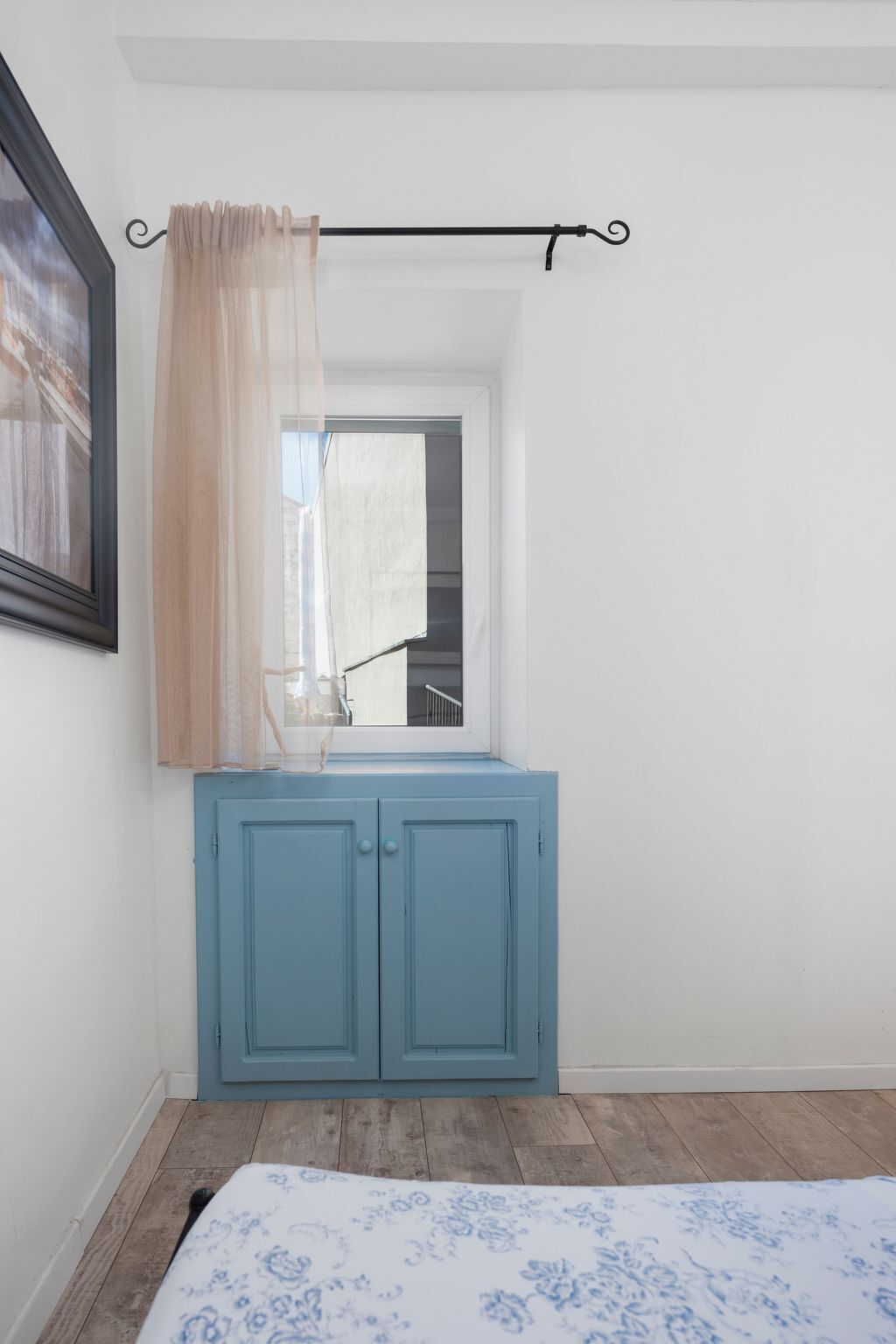 Une chambre à coucher avec un lit, une armoire, une fenêtre donnant sur un beau paysage et un rideau.