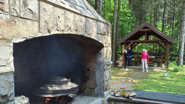 Horno de piedra al aire libre con fuego encendido en su interior, rodeado por una estructura de piedra.