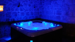 Una vasca idromassaggio con pareti in pietra e illuminazione blu.