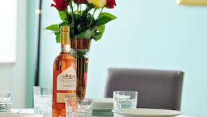 Un tavolo imbandito con piatti, bicchieri e una bottiglia di vino rosato Vina Palihnic.