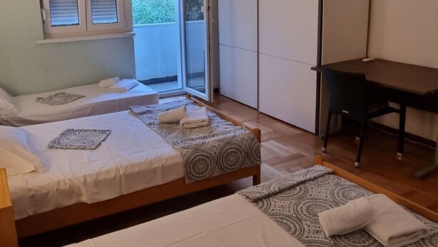 Een slaapkamer met twee bedden, een bureau en een schuifdeur naar een balkon.