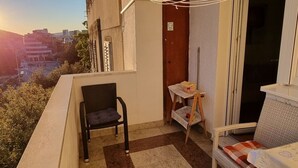 Een balkon met een stoel, een tafeltje en een bank.