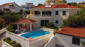 Uma casa de dois andares com piscina, varanda coberta e varanda.