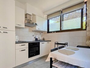Een koelkast, een oven, kookgerei, borden en bestek